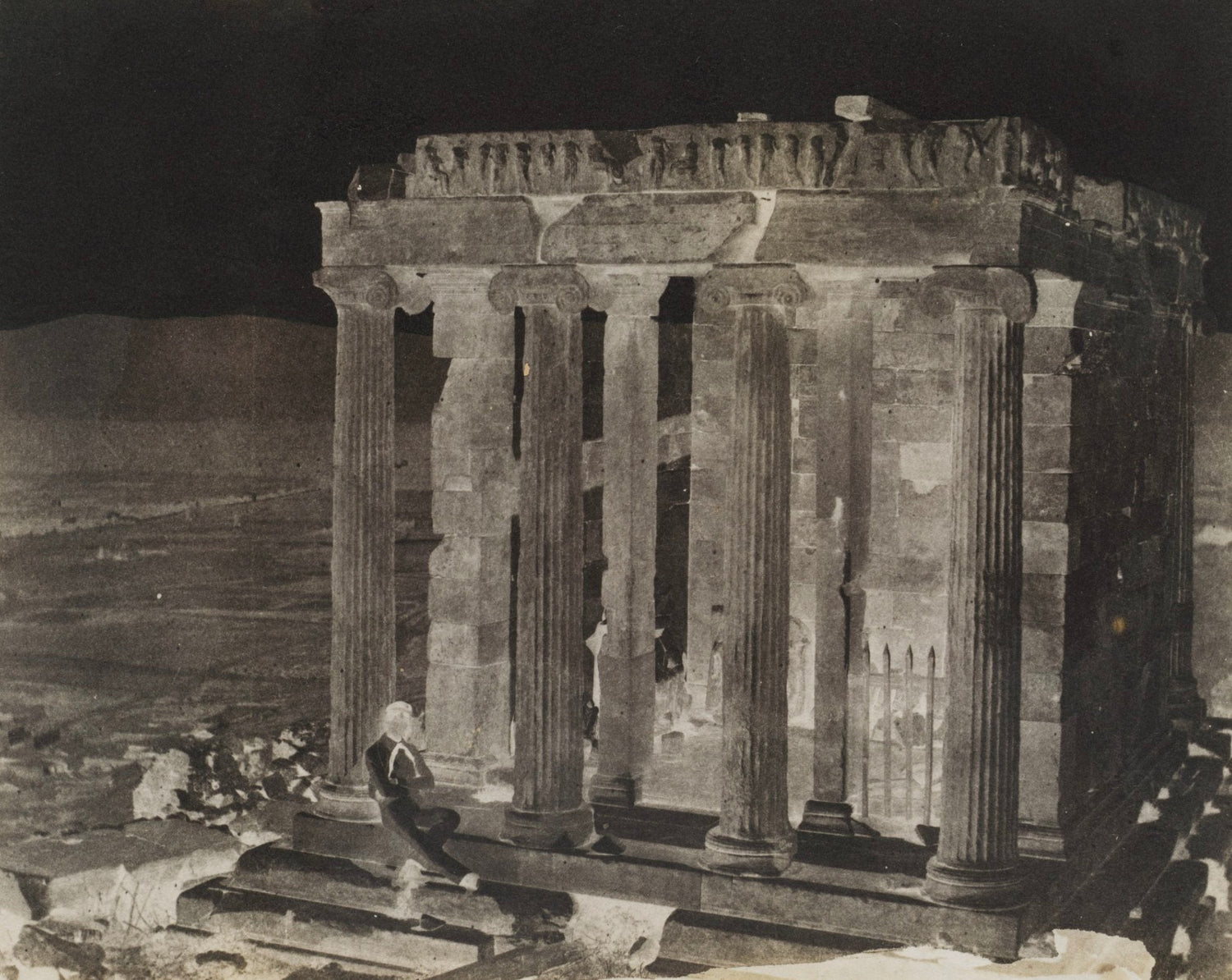 Photograph black and white of ruins with columns and a men sitting 